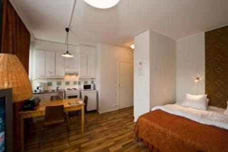 Il comprend une chambre avec un lit, un bureau et une cuisine. dans l'établissement Hotel Homeland, à Tampere