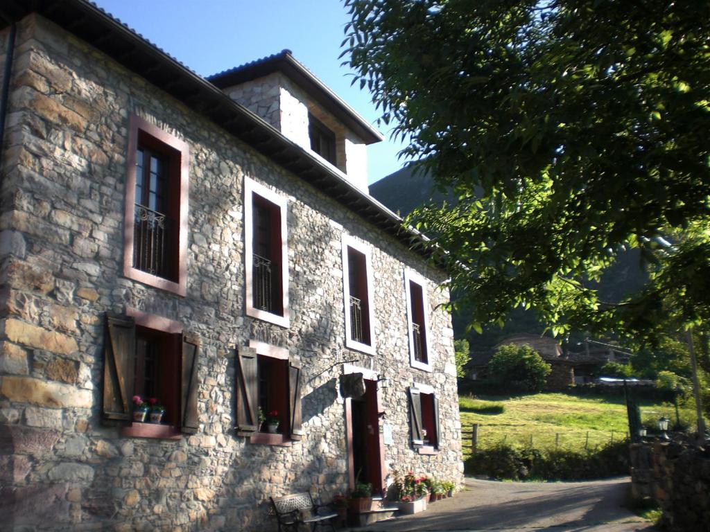 a stone building with windows and flowers on it at Hotel Rural Genestoso in Genestoso