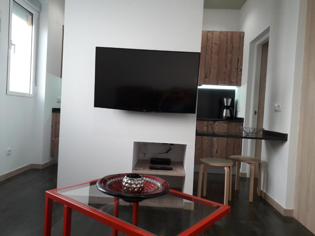 ein Wohnzimmer mit einem Tisch und einem TV an der Wand in der Unterkunft La Casa de Begoña in Madrid