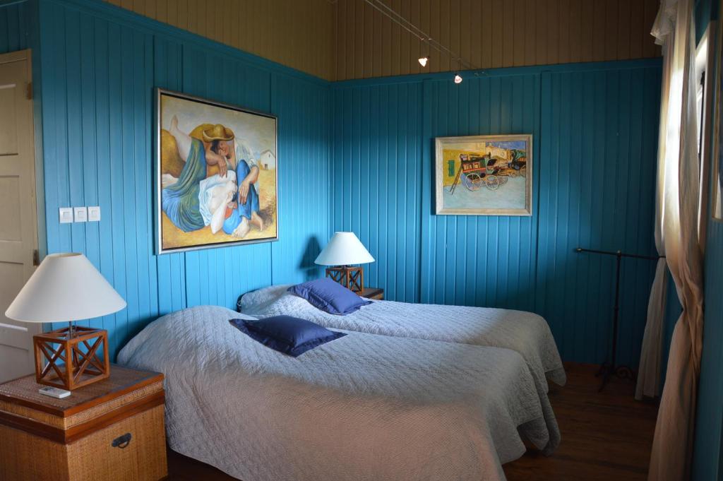 Étables的住宿－Le Chardonneret du Domaine du Moulin 15，一间蓝色卧室,配有一张床和两张墙上的照片