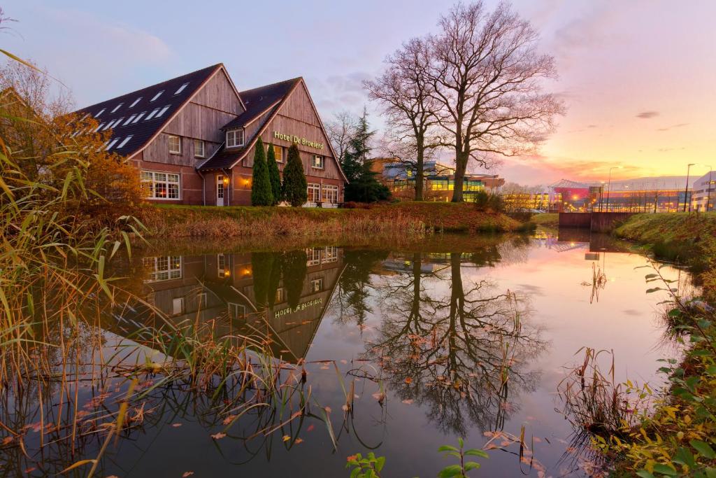 a house with a reflection in the water at sunset at Fletcher Hotel-Restaurant De Broeierd-Enschede in Enschede