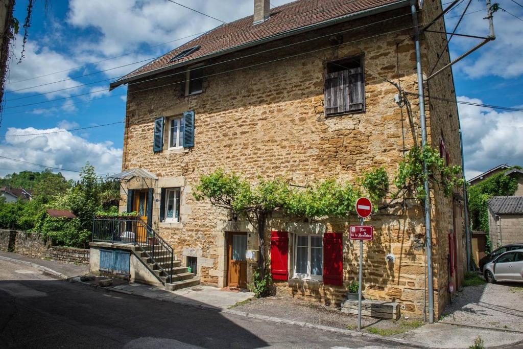 un ancien bâtiment en briques avec une porte rouge dans l'établissement Arbois Le 1876, à Arbois