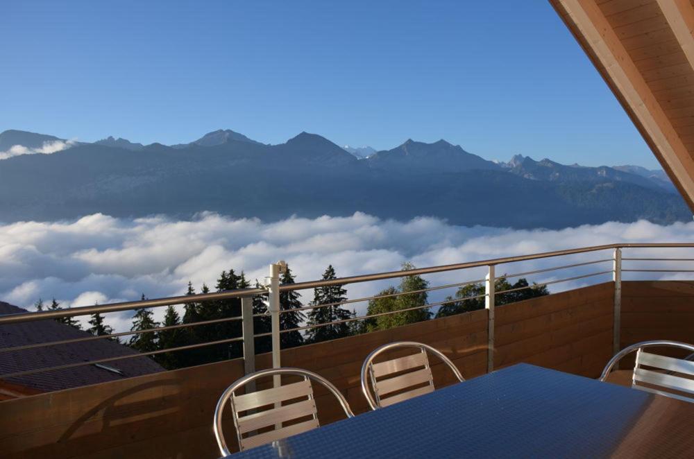 uma mesa e cadeiras numa varanda com vista para as montanhas em Alpenparadies em Beatenberg