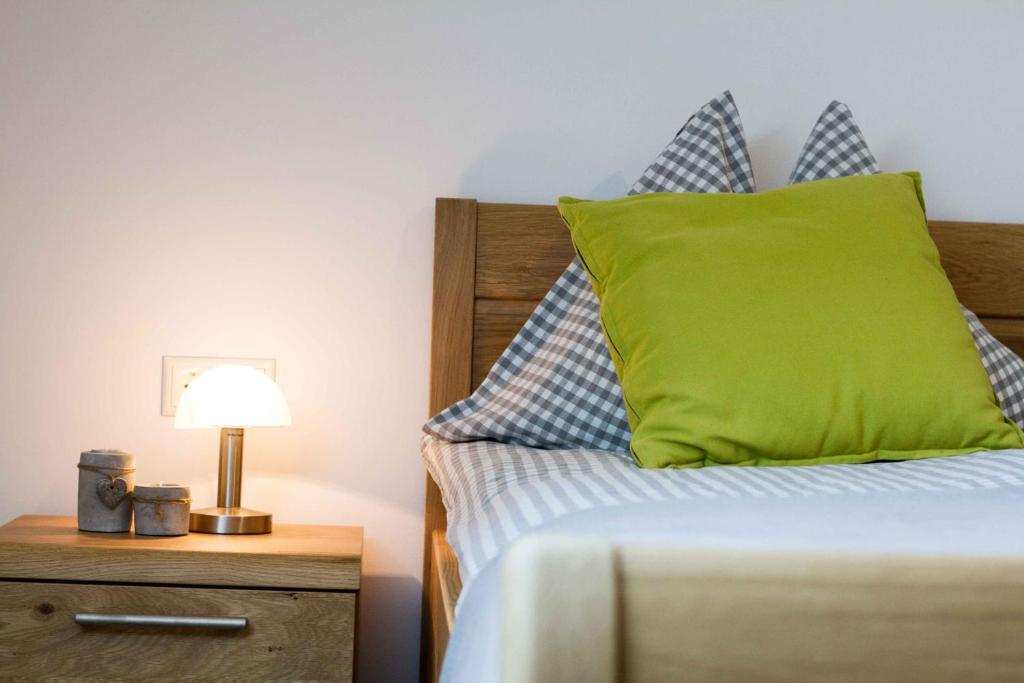 1 dormitorio con cama con almohada verde y mesita de noche en Waldhof Grasel, en Neuhaus