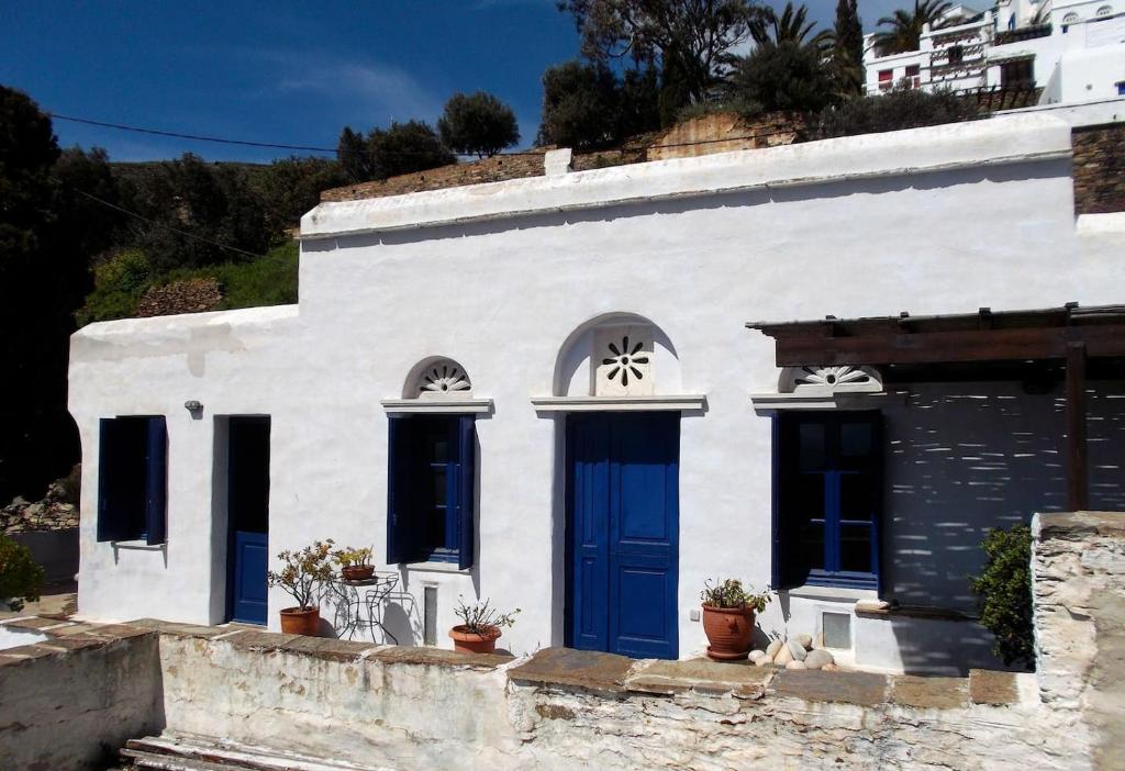 een wit gebouw met blauwe deuren en ramen bij Beautiful house in Tinos Island in Triandáros