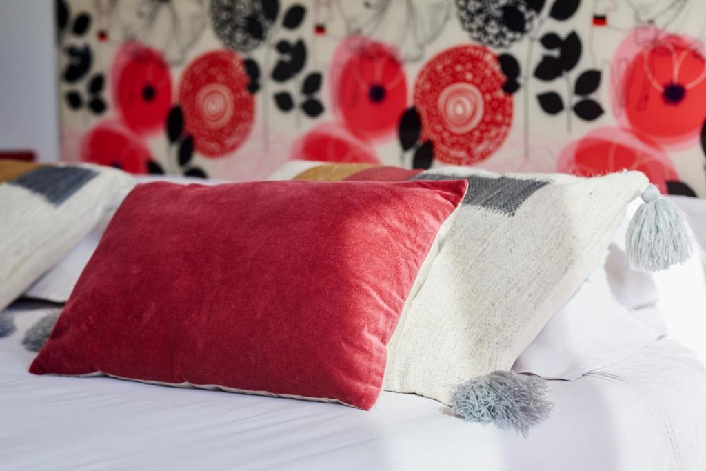 a red pillow on a bed with red and white pillows at Les Appartements Saint-Michel - centre-ville 2 chambres 90m2 avec garage in Saint-Brieuc