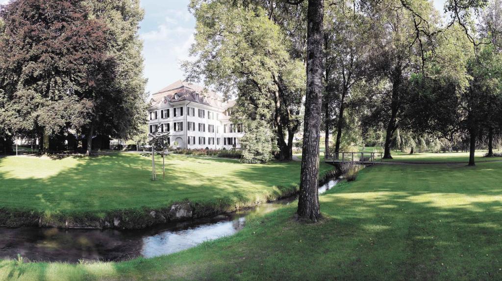 a large white house with a river in front of it at Hotel Schloss Hünigen in Konolfingen