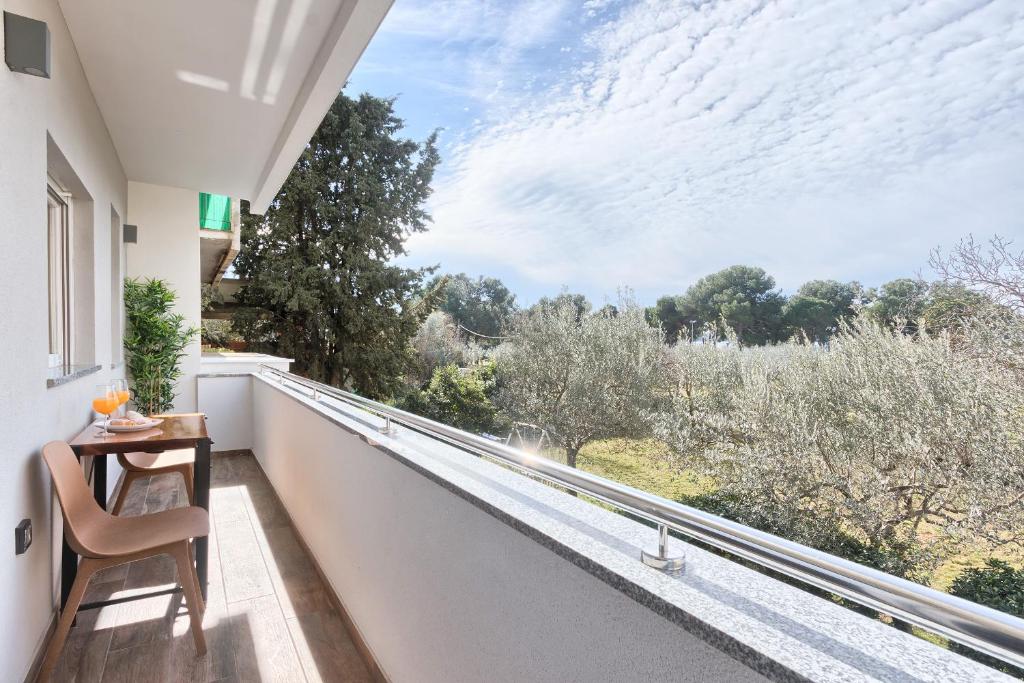 a balcony with a table and a view of trees at rose in Fažana