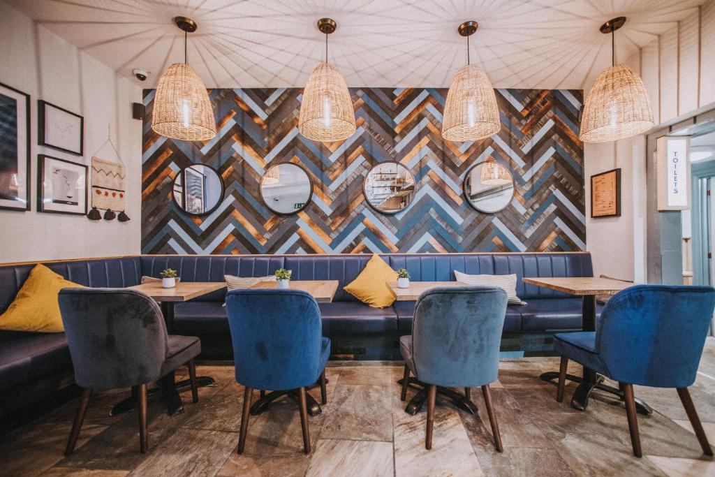 a restaurant with blue chairs and a wall with mirrors at Dukes Inn in Sidmouth