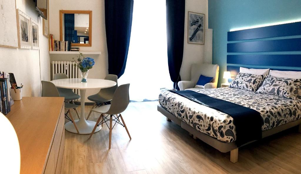 een slaapkamer met een bed en een tafel met stoelen bij Appartamento Blu a Milano zona Ripamonti vicino allo IEO in Milaan