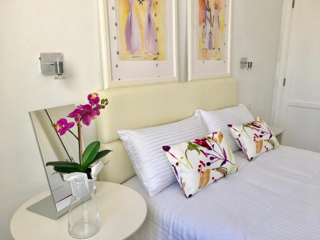 a bed with two pillows and a vase with flowers on it at Apt BARLOVENTO. Near the beach in Tías