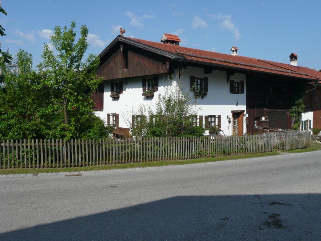 une maison blanche avec une clôture en bois à côté d'une route dans l'établissement Beim Dokterer, Fewo ANNO DAZUMAL, à Halblech