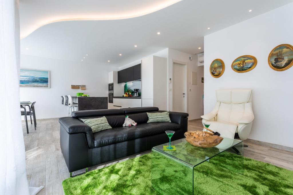 a living room with a black leather couch and a green rug at Villa Valis in Baška