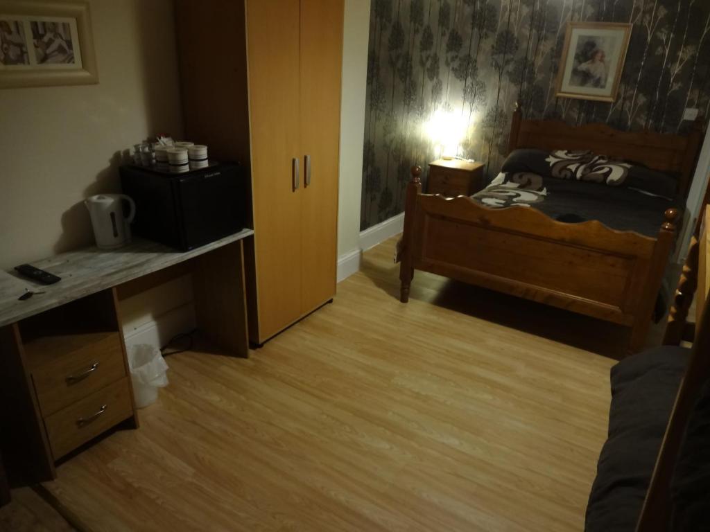 a small bedroom with a bed and a desk and a table at Travellers Rest Motel in Ingoldmells