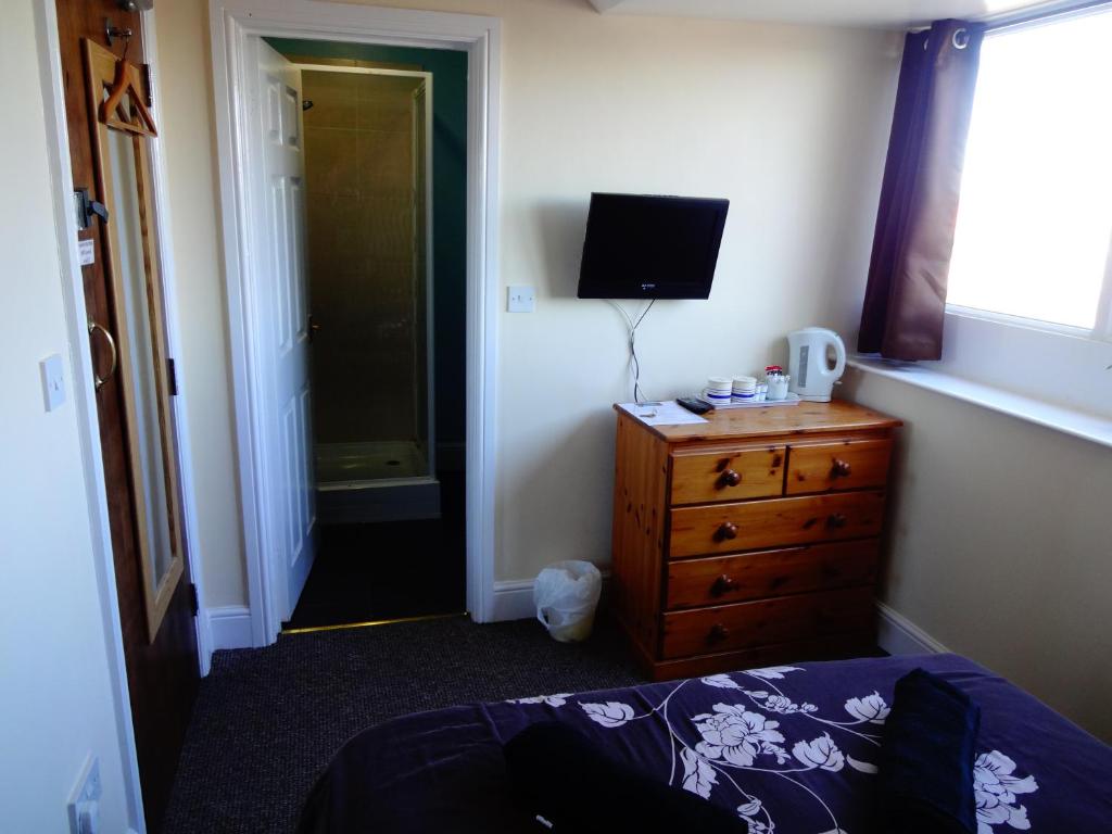 a bedroom with a bed and a dresser and a television at Travellers Rest Motel in Ingoldmells