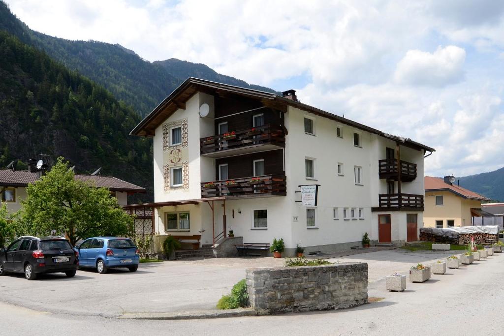 un grand bâtiment blanc avec une horloge. dans l'établissement Haus Gamsblick, à Umhausen