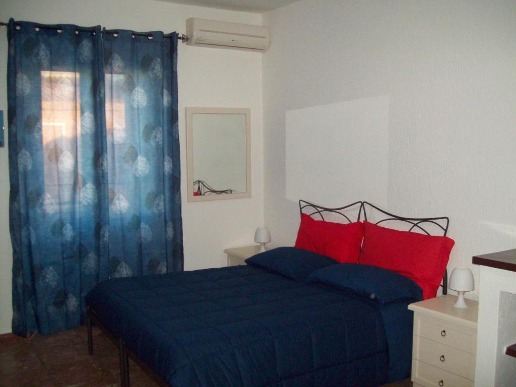 a bedroom with a bed with blue sheets and red pillows at B&B RoGe in Olbia