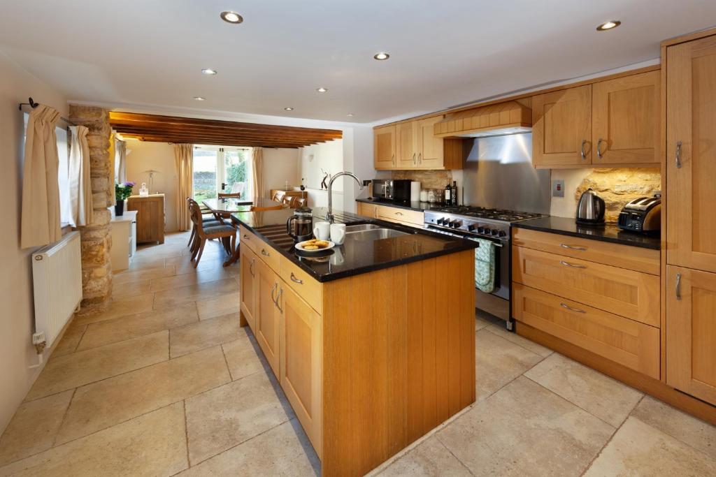 a large kitchen with wooden cabinets and black counter tops at Camside, Chipping Campden - Taswell Retreats in Chipping Campden