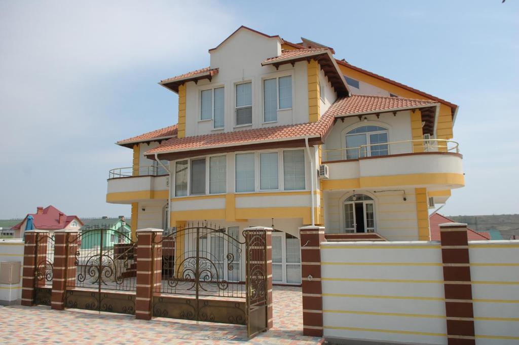 a yellow house with a fence in front of it at Vila Muntenia Hotel in Chişinău