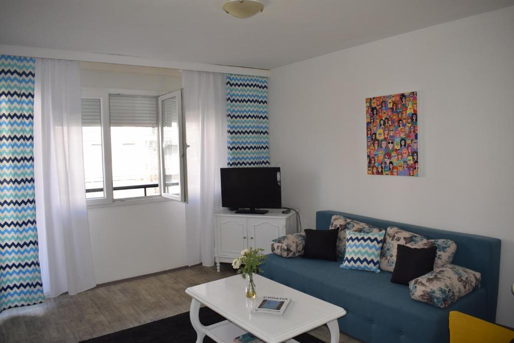 a living room with a blue couch and a tv at Apartment Optimist/Downtown in Split