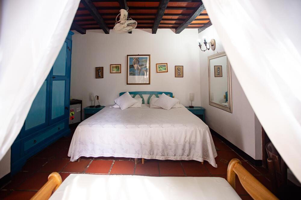 um quarto com uma cama branca e dois bancos em Hotel Casa de Las Palmas em Cartagena de Indias