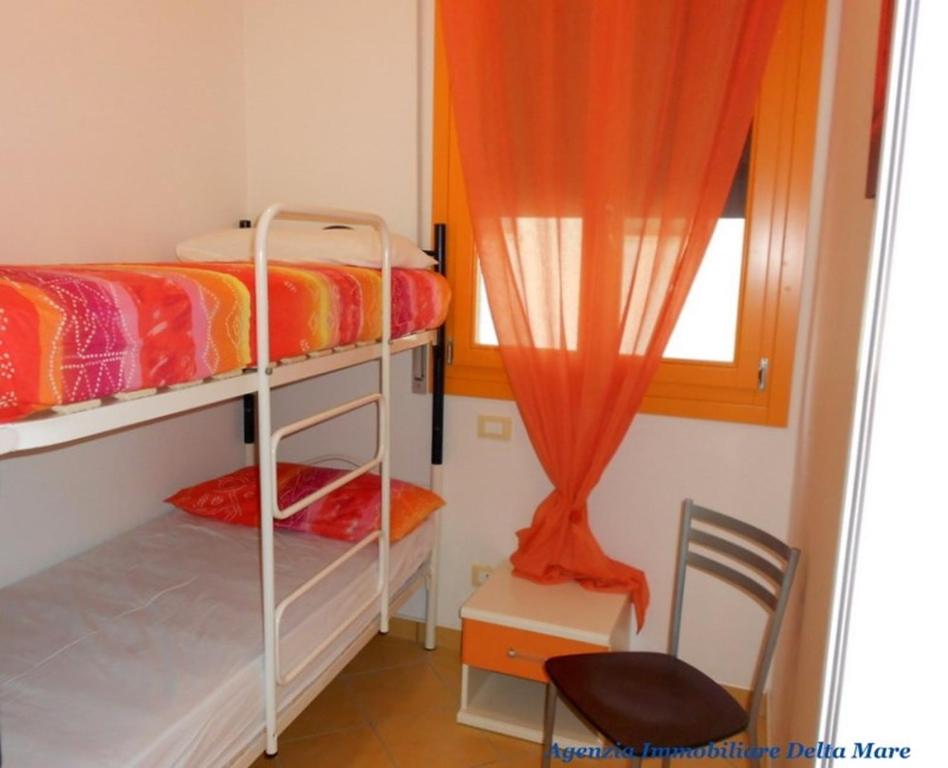 sypialnia z 2 łóżkami piętrowymi, krzesłem i oknem w obiekcie Apartment in Rosolina Mare 24935 w mieście Rosolina Mare