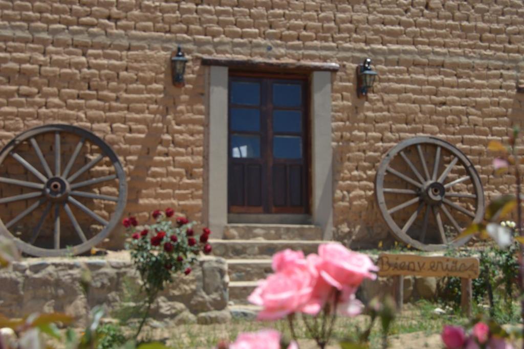 a building with twookedoked wheels in front of a door at Finca Las Pircas Casa de Adobe in Famatina