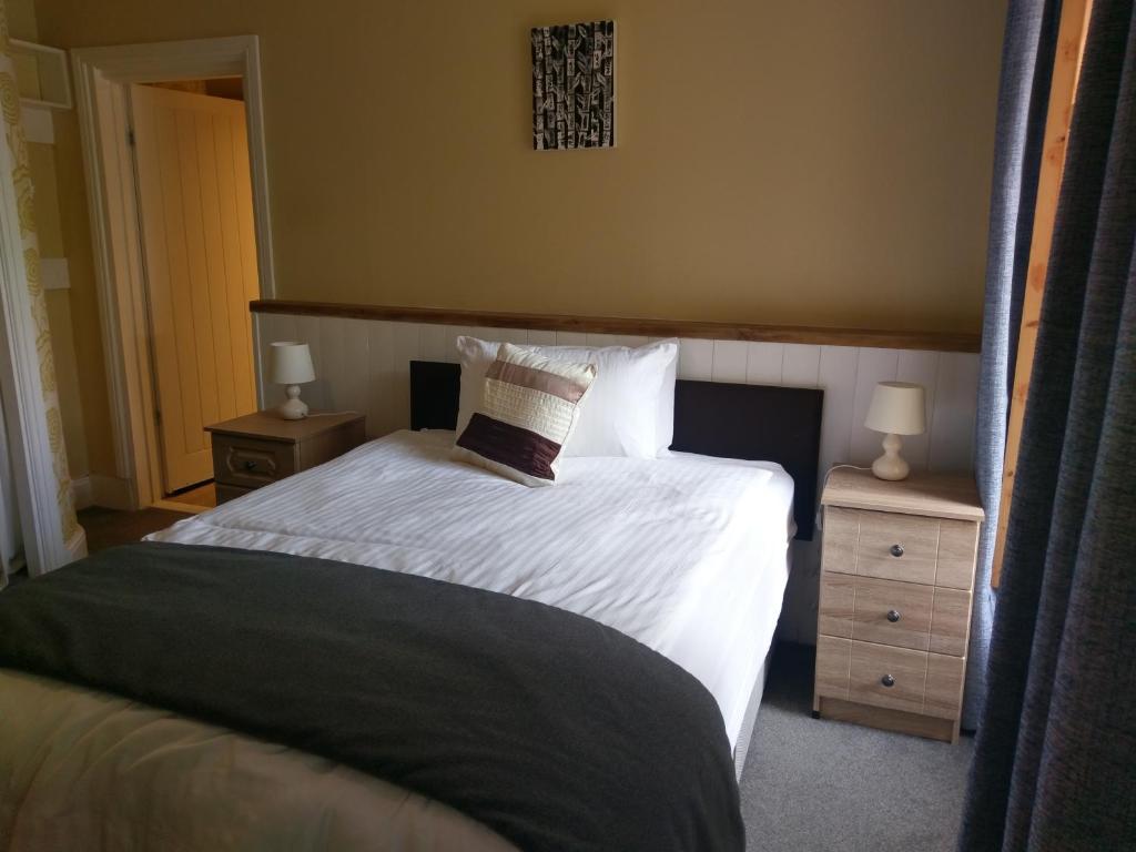 a bedroom with a bed with white sheets and pillows at Gallery Guest House in Plymouth