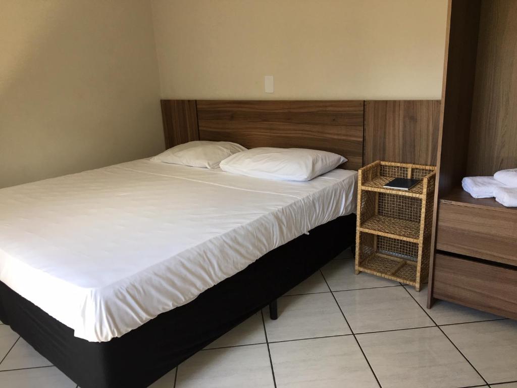 a bedroom with a large bed with a wooden headboard at Hotel Renavi in Além Paraíba