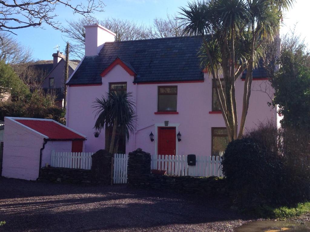 a white house with a white fence and a palm tree at The Old Barracks,Caherdaniel in Caherdaniel