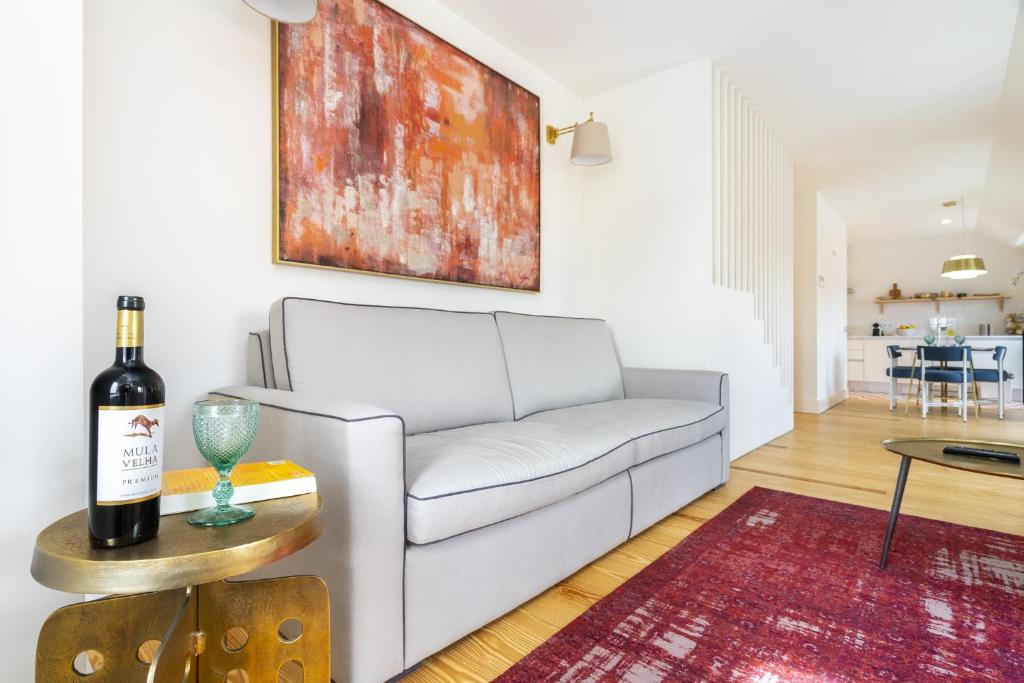 een woonkamer met een witte bank en een fles wijn bij Velvet Dream Apartment in Lissabon