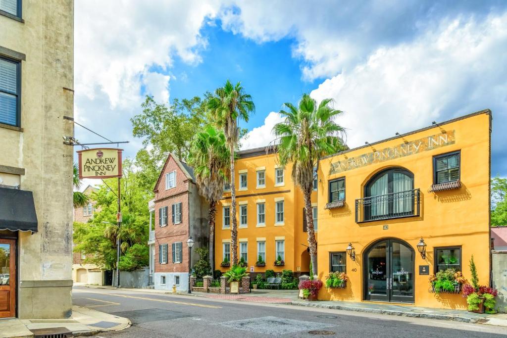 ein gelbes Gebäude auf einer Straße mit Palmen in der Unterkunft Andrew Pinckney Inn in Charleston