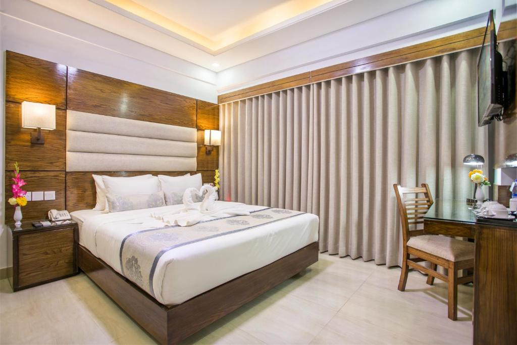 a bedroom with a large bed and a desk and a chair at White Palace Hotel in Dhaka