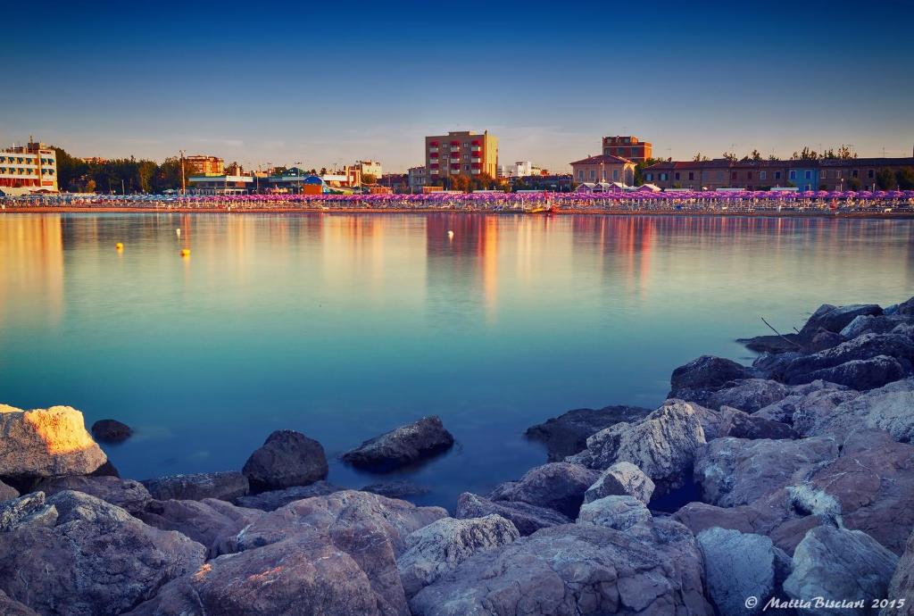 a large body of water with rocks and buildings at Hotel Elisabeth Due in Fano