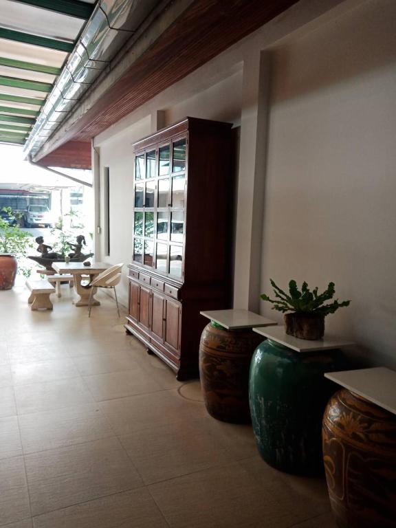 A covered hotel corridor with a wooden cabinet, ceramic tables, and outdoor seating.