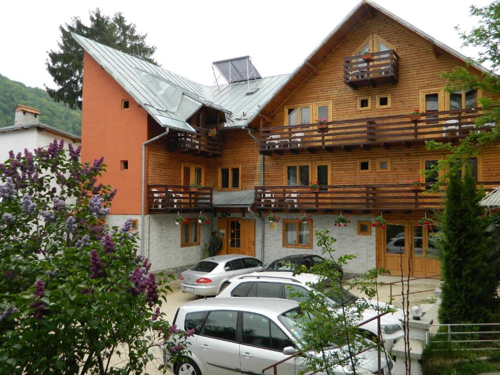 a building with cars parked in a parking lot at Pensiunea La Cristina in Sinaia