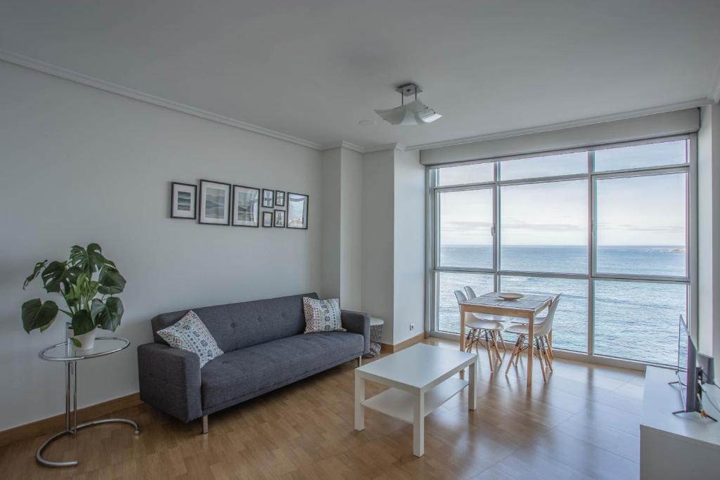 ein Wohnzimmer mit einem Sofa und einem Tisch in der Unterkunft APARTAMENTO EN PRIMERA LINEA DE PLAYA RiAZOR in A Coruña