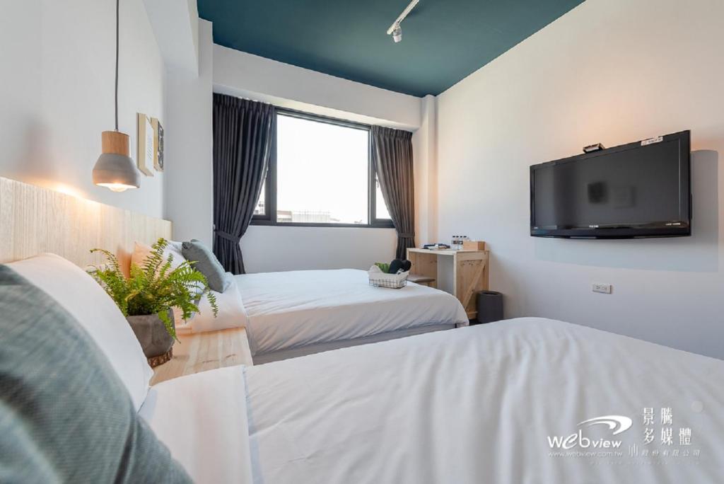 a hotel room with two beds and a flat screen tv at Wu Ting Stay in Hualien City