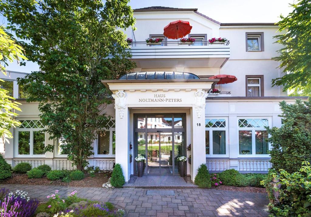 un bâtiment blanc avec une porte et un parapluie rouge dans l'établissement Hotel Noltmann-Peters, à Bad Rothenfelde