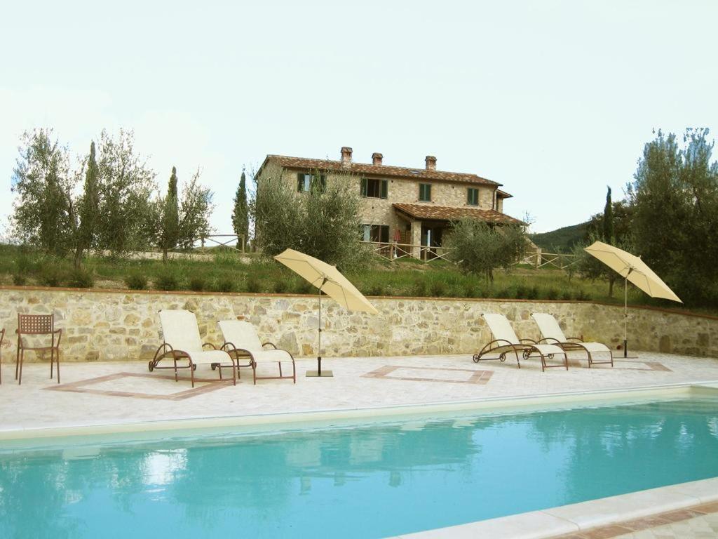 um grupo de cadeiras e guarda-sóis ao lado de uma piscina em La Coccinella em San Venanzo