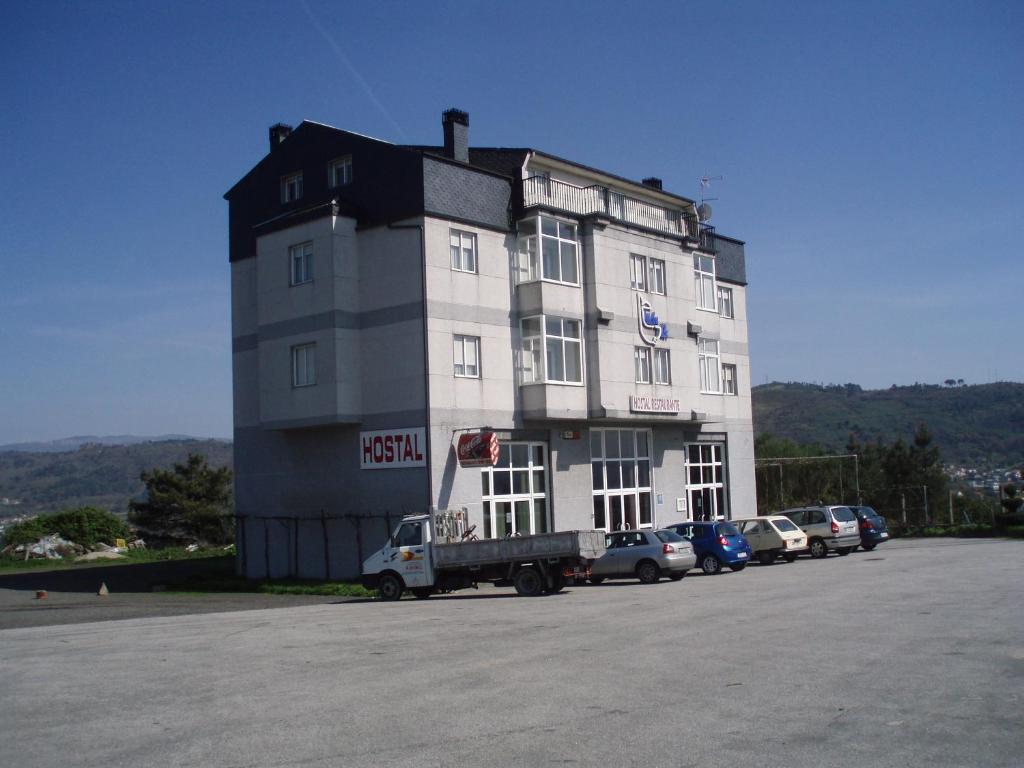 un grand bâtiment blanc avec des voitures garées dans un parking dans l'établissement Hostal Mobydick2, à Ourense