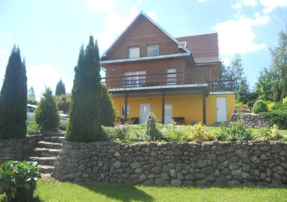 a large house with a stone fence in front of it at Agroturystyka Na Skarpie in Wiżajny