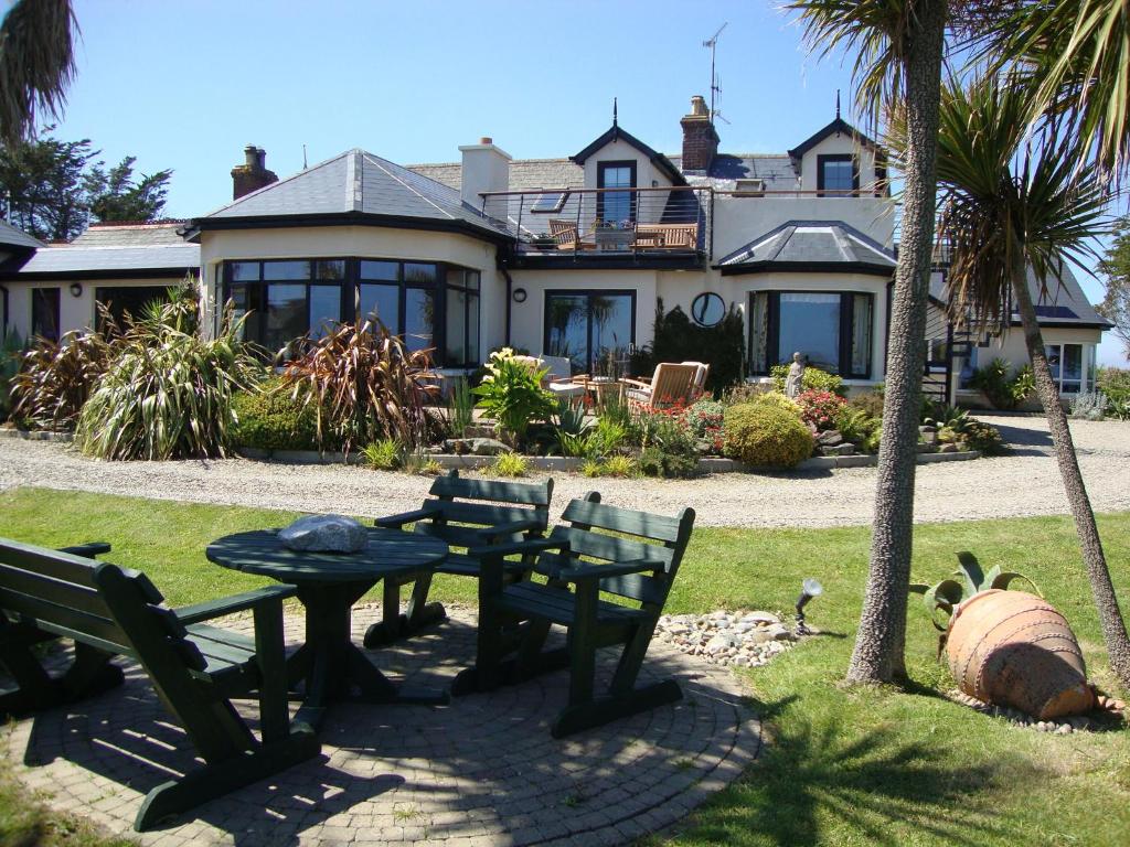 a house with a table and benches in front of it at Clifford House B & B in Rosslare