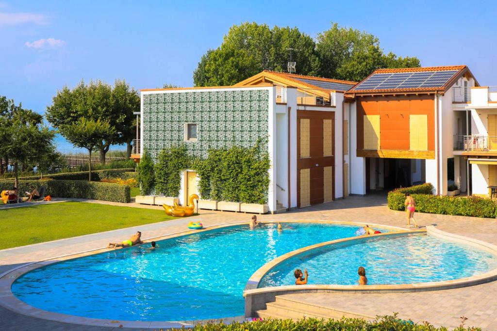 Castelnuovo di Veronaにあるgardaverhuur - La Perla Sul Lagoの人が入る建物の前のスイミングプール