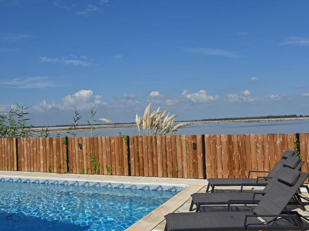 a swimming pool with two chairs and a fence at Luxury holiday home with private pool in Le Grau-du-Roi