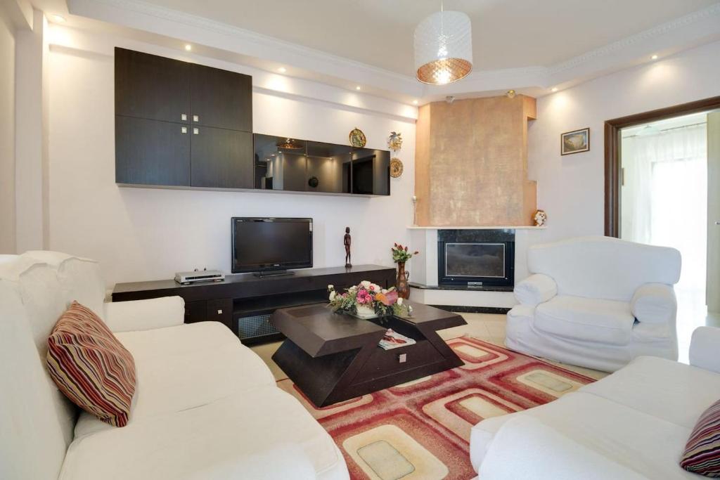 a living room with two white couches and a tv at Villa Natali in Flogita