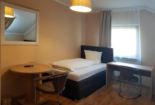 a small room with a bed and a table and a tableablish at Hotel-Residenz Oberurseler Hof in Oberursel