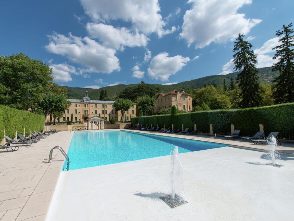 a swimming pool with a fountain in front of a building at Historical castle in Montbrun les Bains with pool in Montbrun-les-Bains