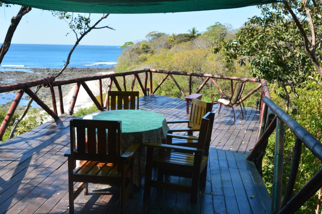 a wooden deck with a table and chairs and the ocean at Treetops B & B Inn in San Juanillo