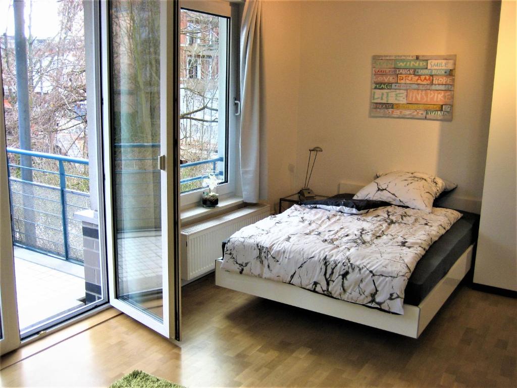 a bedroom with a bed and a large window at Hochwertiges Apartment im Grünen, zentral gelegen, ruhig, Balkon in Hannover